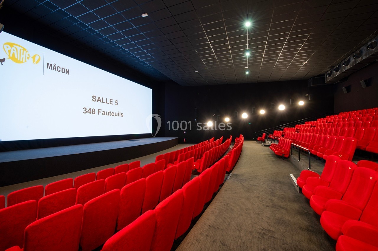 Salle de cinéma avec des rangées de fauteuils rouges vides, écran affichant ’Salle 5, 348 fauteuils’.