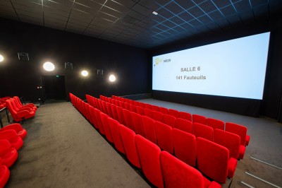 Une personne sert un verre de jus d'orange sur une table garnie de carafes, verres et viennoiseries.