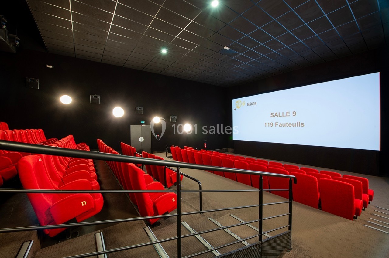 Salle de cinéma vide avec des sièges rouges, un écran affichant ’Salle 9, 119 fauteuils’ et un éclairage tamisé.