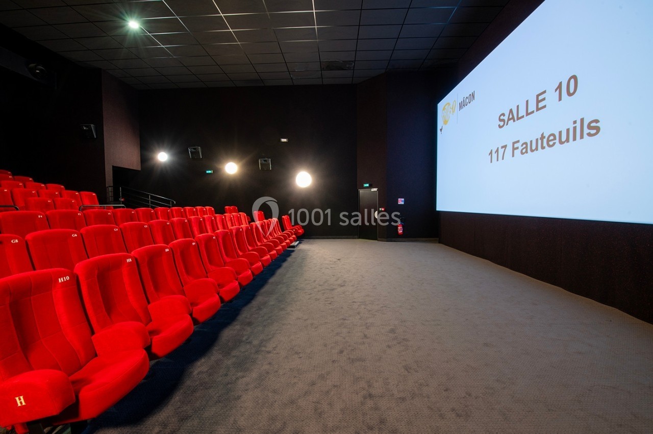 Salle de cinéma avec des rangées de fauteuils rouges, un écran affichant ’Salle 10 - 117 Fauteuils’ et un sol moquetté.