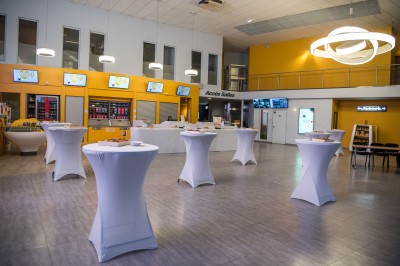 Une personne sert un verre de jus d'orange sur une table garnie de carafes, verres et viennoiseries.