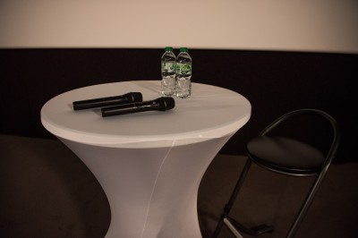 Une personne sert un verre de jus d'orange sur une table garnie de carafes, verres et viennoiseries.