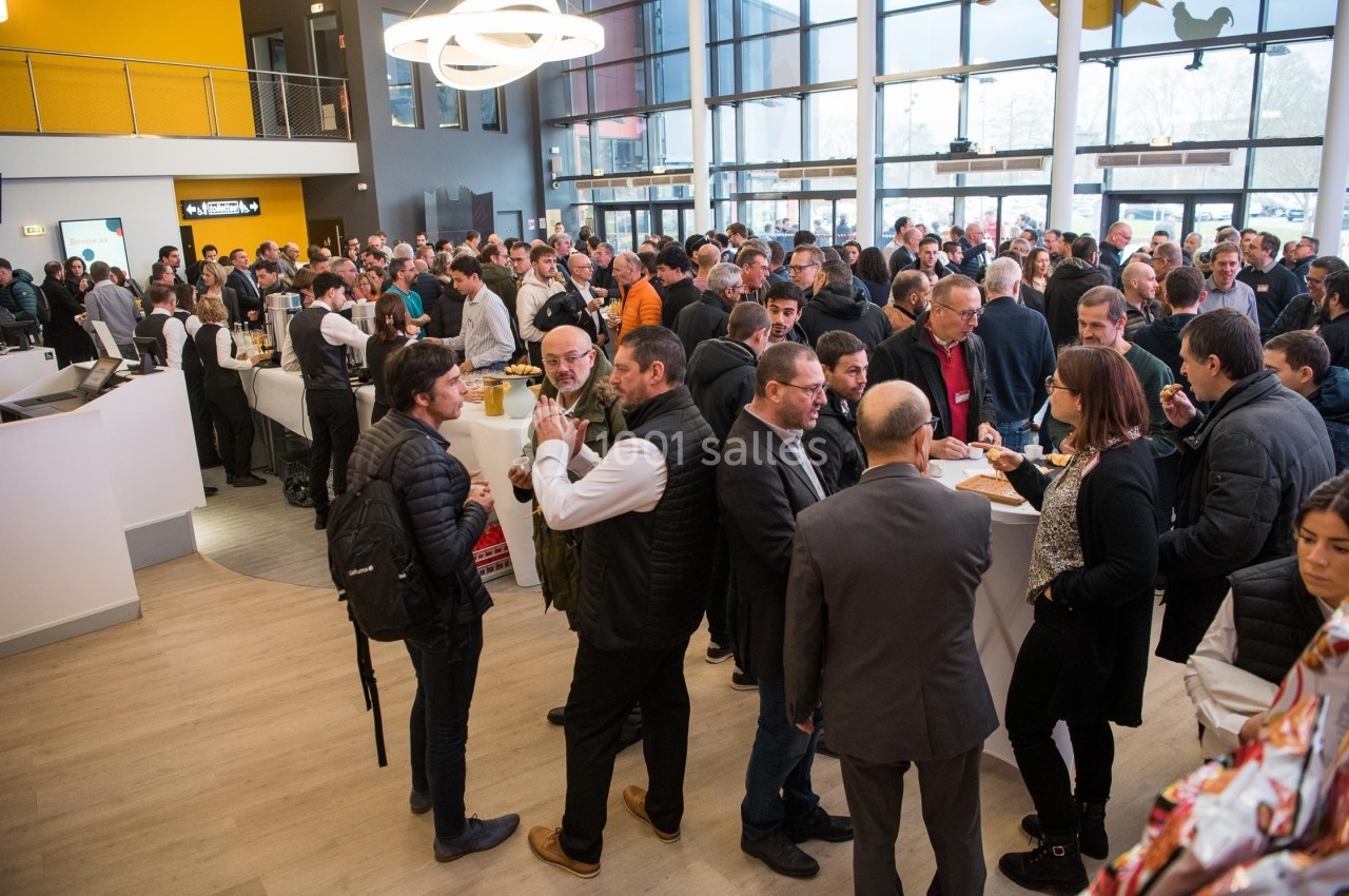 Un groupe de personnes échange dans un espace intérieur lumineux lors d'un événement ou d'une réunion.