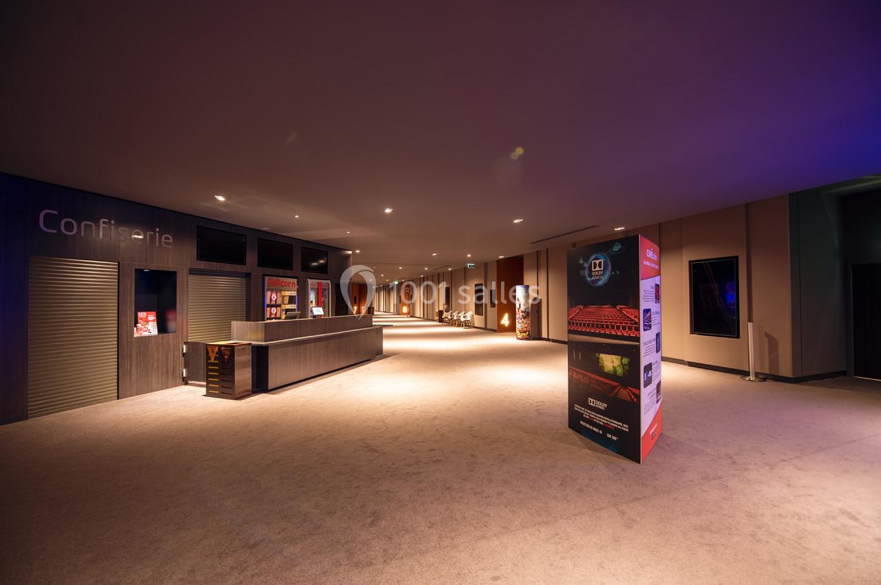 Hall spacieux avec comptoir de confiserie fermé, éclairage tamisé et affiches promotionnelles au premier plan.