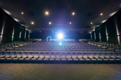 Façade d'un cinéma avec un parking au premier plan, quelques arbres et un ciel dégagé en arrière-plan.