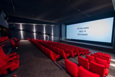Façade d'un cinéma avec un parking au premier plan, quelques arbres et un ciel dégagé en arrière-plan.