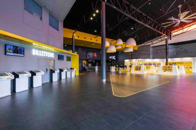 Façade d'un cinéma avec un parking au premier plan, quelques arbres et un ciel dégagé en arrière-plan.