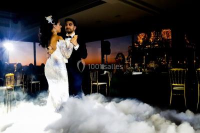 Un couple danse au milieu d'une piste entourée de fumée, tandis qu'un musicien joue du saxophone en avant-plan.