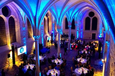 Vue d'une régie DJ avec platines et ordinateur, face à une salle éclairée en violet lors d'un événement festif.