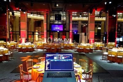 Vue d'une régie DJ avec platines et ordinateur, face à une salle éclairée en violet lors d'un événement festif.