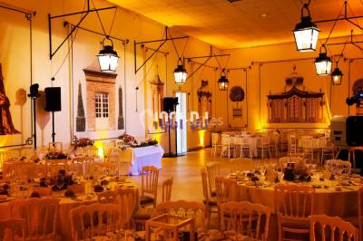Vue d'une régie DJ avec platines et ordinateur, face à une salle éclairée en violet lors d'un événement festif.