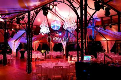 Vue d'une régie DJ avec platines et ordinateur, face à une salle éclairée en violet lors d'un événement festif.