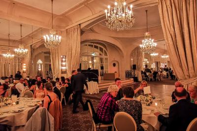 Vue d'une régie DJ avec platines et ordinateur, face à une salle éclairée en violet lors d'un événement festif.