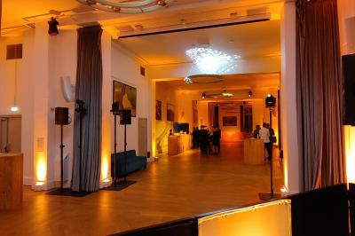 Vue d'une régie DJ avec platines et ordinateur, face à une salle éclairée en violet lors d'un événement festif.