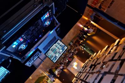 Vue d'une régie DJ avec platines et ordinateur, face à une salle éclairée en violet lors d'un événement festif.