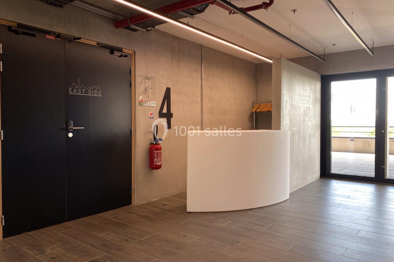 Entrée d'un étage avec porte noire, numéro ’4’ sur le mur, comptoir blanc et sortie vitrée donnant sur l'extérieur.