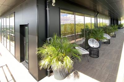Terrasse moderne avec mobilier en rotin, plantes en pot et fresque murale représentant une skyline urbaine.