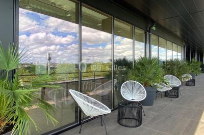 Terrasse moderne avec mobilier en rotin, plantes en pot et fresque murale représentant une skyline urbaine.
