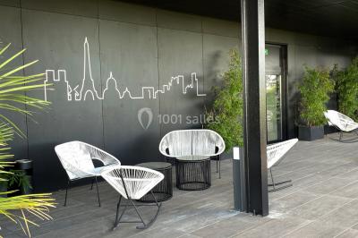 Terrasse moderne avec mobilier en rotin, plantes en pot et fresque murale représentant une skyline urbaine.