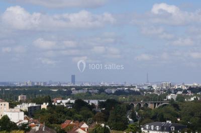 Terrasse moderne avec mobilier en rotin, plantes en pot et fresque murale représentant une skyline urbaine.