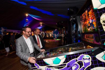 Miniature ArScénique #11 Homme sur une planche de surf simulant une vague géante gonflable dans un espace intérieur éclairé.