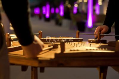Miniature ArScénique #12 Homme sur une planche de surf simulant une vague géante gonflable dans un espace intérieur éclairé.