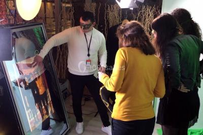 Miniature ArScénique #9 Homme sur une planche de surf simulant une vague géante gonflable dans un espace intérieur éclairé.