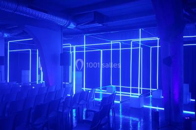 Miniature ArScénique #6 Homme sur une planche de surf simulant une vague géante gonflable dans un espace intérieur éclairé.