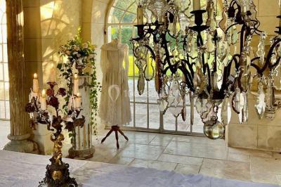 Portail en fer forgé ouvert sur un chemin verdoyant bordé d'arbres et de fleurs sauvages.