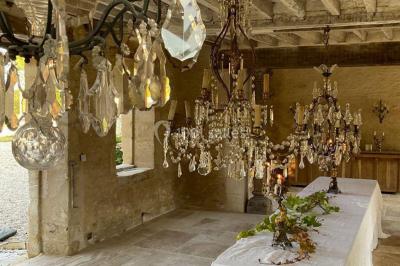 Portail en fer forgé ouvert sur un chemin verdoyant bordé d'arbres et de fleurs sauvages.