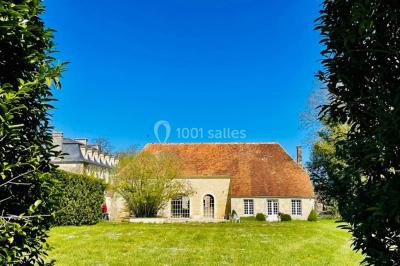 Portail en fer forgé ouvert sur un chemin verdoyant bordé d'arbres et de fleurs sauvages.