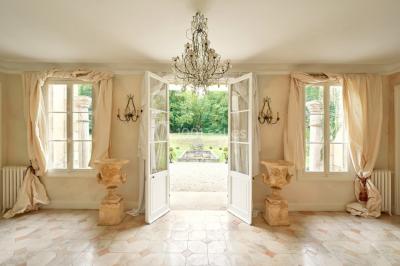 Portail en fer forgé ouvert sur un chemin verdoyant bordé d'arbres et de fleurs sauvages.