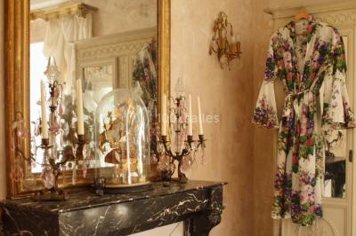 Portail en fer forgé ouvert sur un chemin verdoyant bordé d'arbres et de fleurs sauvages.