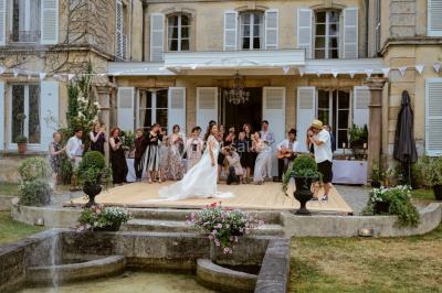 Portail en fer forgé ouvert sur un chemin verdoyant bordé d'arbres et de fleurs sauvages.