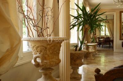 Portail en fer forgé ouvert sur un chemin verdoyant bordé d'arbres et de fleurs sauvages.