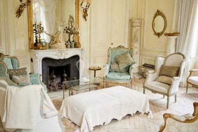 Portail en fer forgé ouvert sur un chemin verdoyant bordé d'arbres et de fleurs sauvages.