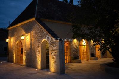 Portail en fer forgé ouvert sur un chemin verdoyant bordé d'arbres et de fleurs sauvages.