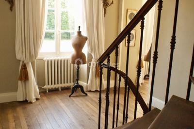 Portail en fer forgé ouvert sur un chemin verdoyant bordé d'arbres et de fleurs sauvages.