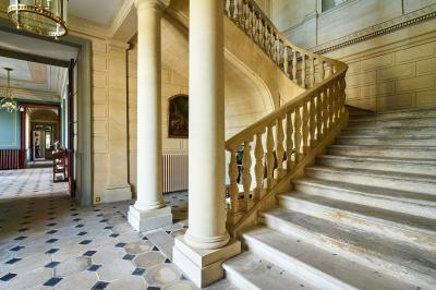 Salle élégante avec parquet en bois, murs ornés de moulures, lustres et mobilier classique.