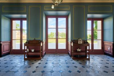 Salle élégante avec parquet en bois, murs ornés de moulures, lustres et mobilier classique.