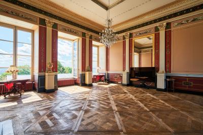 Salle élégante avec parquet en bois, murs ornés de moulures, lustres et mobilier classique.
