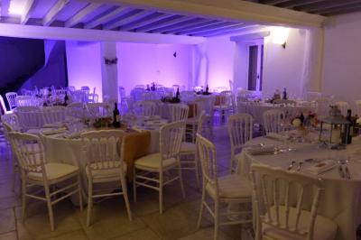 Terrasse extérieure avec pergola en bois, tables et chaises sur sol gravillonné, près d'un mur en pierre et d'un arbre.
