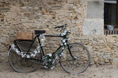 Terrasse extérieure avec pergola en bois, tables et chaises sur sol gravillonné, près d'un mur en pierre et d'un arbre.