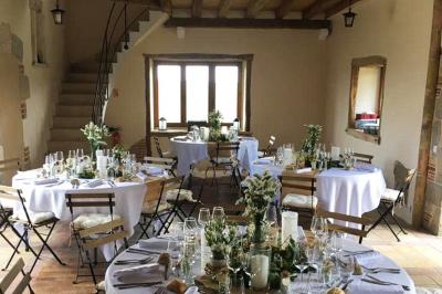 Terrasse extérieure avec pergola en bois, tables et chaises sur sol gravillonné, près d'un mur en pierre et d'un arbre.