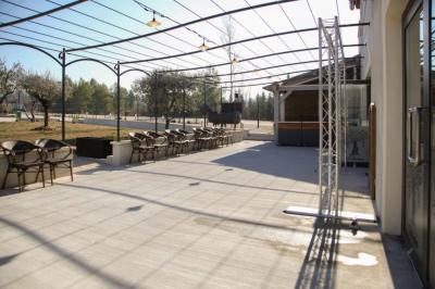 Salle d'attente lumineuse avec banquettes rouges et grises, table en marbre blanc et écran mural.