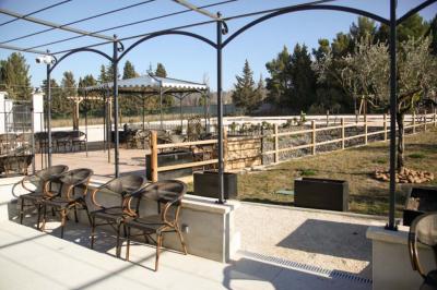 Salle d'attente lumineuse avec banquettes rouges et grises, table en marbre blanc et écran mural.