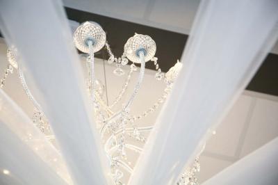 Salle d'attente lumineuse avec banquettes rouges et grises, table en marbre blanc et écran mural.