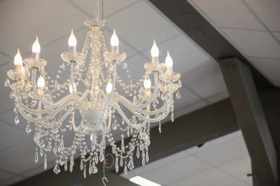 Salle d'attente lumineuse avec banquettes rouges et grises, table en marbre blanc et écran mural.