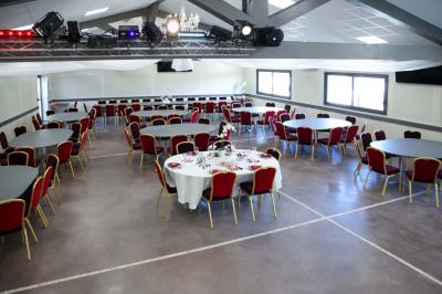Salle d'attente lumineuse avec banquettes rouges et grises, table en marbre blanc et écran mural.