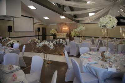 Salle d'attente lumineuse avec banquettes rouges et grises, table en marbre blanc et écran mural.